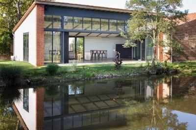 Salle de réception décorée pour un mariage, avec tables rondes, nappes blanches et guirlandes lumineuses au plafond.