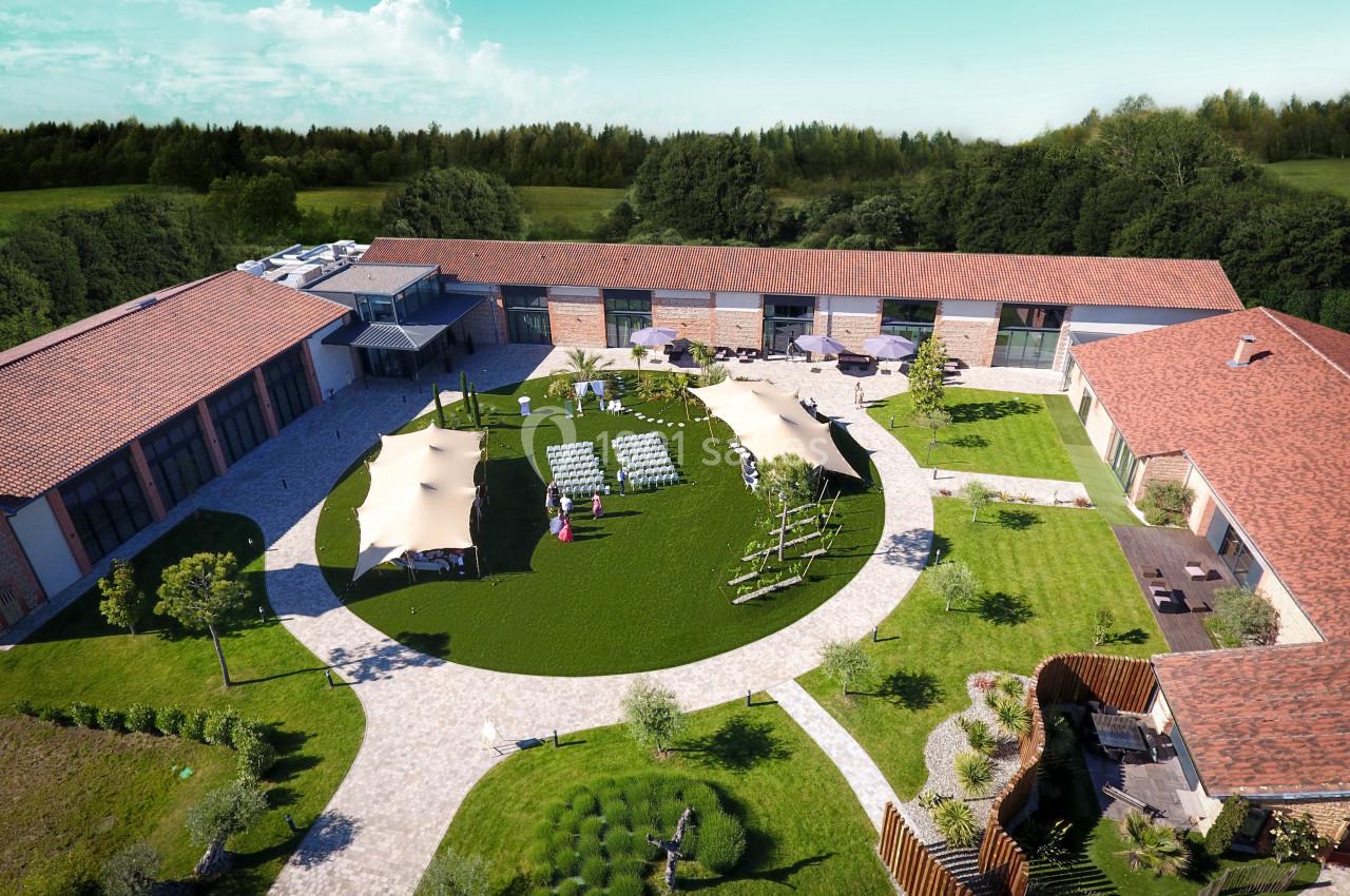 Vue aérienne d'une cour intérieure aménagée avec pelouse, parasols, chaises et bâtiments en briques autour.