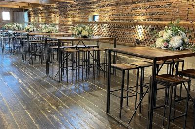 Salle de réception décorée pour un mariage, avec tables rondes, nappes blanches et guirlandes lumineuses au plafond.