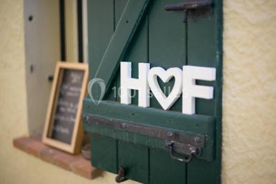 Un couple habillé élégamment, la femme en robe blanche et l'homme en costume, pose dans une pièce lumineuse.