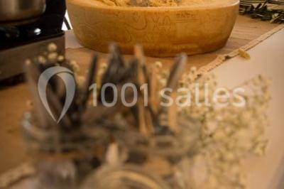 Un couple habillé élégamment, la femme en robe blanche et l'homme en costume, pose dans une pièce lumineuse.