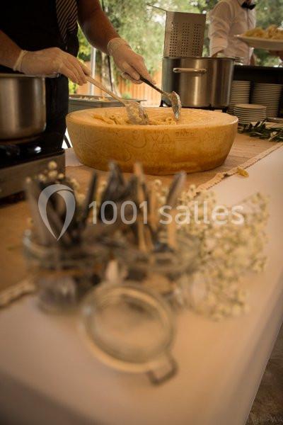 Service de pâtes dans une meule de fromage, avec des couverts et décorations florales sur une table.