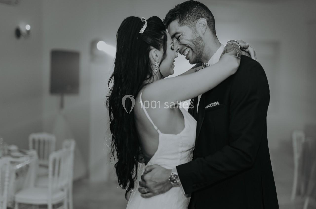 Un couple en tenue de mariage danse ensemble dans une salle éclairée de manière douce.