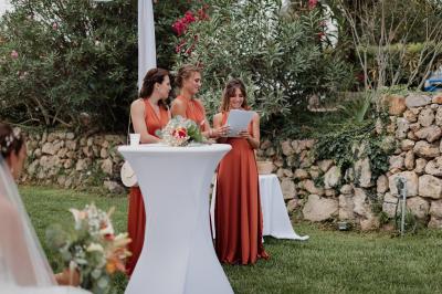 Un couple habillé élégamment, la femme en robe blanche et l'homme en costume, pose dans une pièce lumineuse.