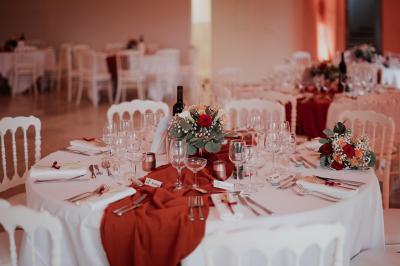 Un couple habillé élégamment, la femme en robe blanche et l'homme en costume, pose dans une pièce lumineuse.