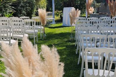 Un couple habillé élégamment, la femme en robe blanche et l'homme en costume, pose dans une pièce lumineuse.