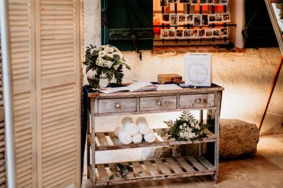Un couple habillé élégamment, la femme en robe blanche et l'homme en costume, pose dans une pièce lumineuse.