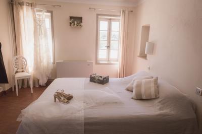 Un couple habillé élégamment, la femme en robe blanche et l'homme en costume, pose dans une pièce lumineuse.