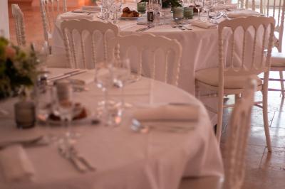 Un couple habillé élégamment, la femme en robe blanche et l'homme en costume, pose dans une pièce lumineuse.