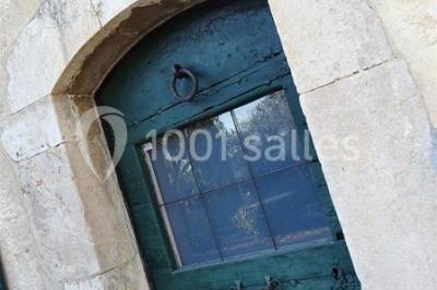Un couple habillé élégamment, la femme en robe blanche et l'homme en costume, pose dans une pièce lumineuse.