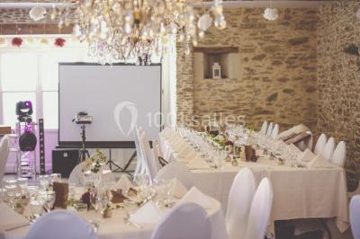 Bouquet de fleurs blanches et roses dans un pichet en terre cuite, posé dans une caisse en bois entourée de verdure.