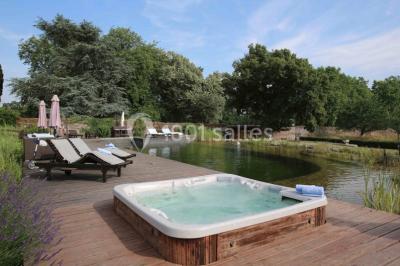 Bouquet de fleurs blanches et roses dans un pichet en terre cuite, posé dans une caisse en bois entourée de verdure.