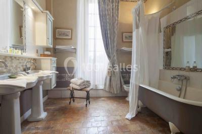 Bouquet de fleurs blanches et roses dans un pichet en terre cuite, posé dans une caisse en bois entourée de verdure.