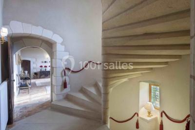 Bouquet de fleurs blanches et roses dans un pichet en terre cuite, posé dans une caisse en bois entourée de verdure.