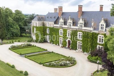 Bouquet de fleurs blanches et roses dans un pichet en terre cuite, posé dans une caisse en bois entourée de verdure.