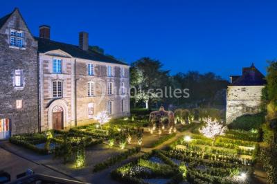 Bouquet de fleurs blanches et roses dans un pichet en terre cuite, posé dans une caisse en bois entourée de verdure.