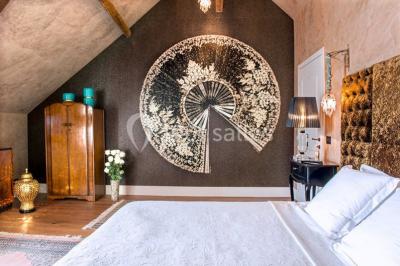 Bouquet de fleurs blanches et roses dans un pichet en terre cuite, posé dans une caisse en bois entourée de verdure.