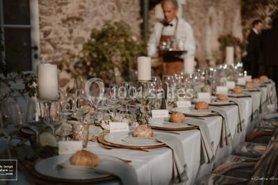 Bouquet de fleurs blanches et roses dans un pichet en terre cuite, posé dans une caisse en bois entourée de verdure.