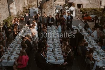 Bouquet de fleurs blanches et roses dans un pichet en terre cuite, posé dans une caisse en bois entourée de verdure.