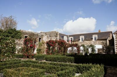 Bouquet de fleurs blanches et roses dans un pichet en terre cuite, posé dans une caisse en bois entourée de verdure.