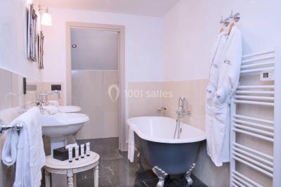 Bouquet de fleurs blanches et roses dans un pichet en terre cuite, posé dans une caisse en bois entourée de verdure.