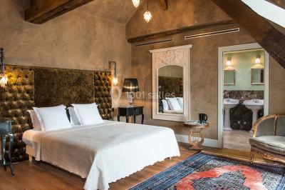 Bouquet de fleurs blanches et roses dans un pichet en terre cuite, posé dans une caisse en bois entourée de verdure.