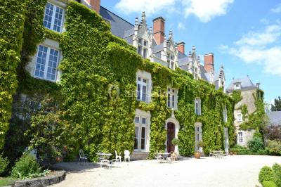 Bouquet de fleurs blanches et roses dans un pichet en terre cuite, posé dans une caisse en bois entourée de verdure.