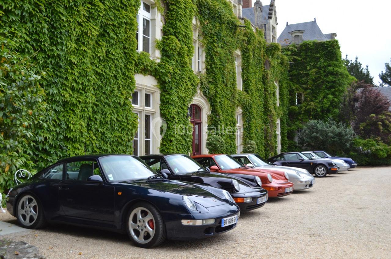 Alignement de voitures anciennes garées devant une façade de bâtiment recouverte de lierre.