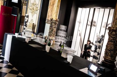 Salle élégante avec tables rondes dressées, chaises blanches et grand portrait en noir et blanc en arrière-plan.
