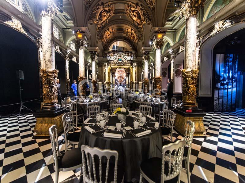 Salle de réception élégante avec tables dressées, colonnes ornées et plafond richement décoré.