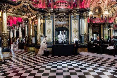 Salle élégante avec tables rondes dressées, chaises blanches et grand portrait en noir et blanc en arrière-plan.