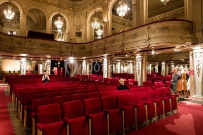 Salle élégante avec tables rondes dressées, chaises blanches et grand portrait en noir et blanc en arrière-plan.