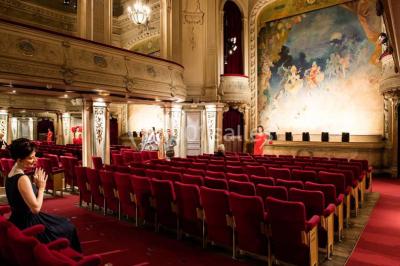 Salle élégante avec tables rondes dressées, chaises blanches et grand portrait en noir et blanc en arrière-plan.
