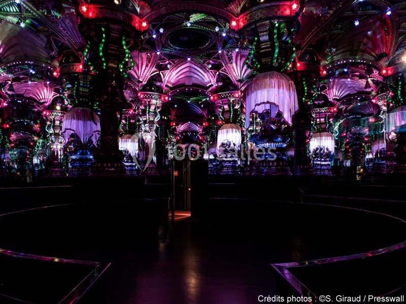 Salle sombre ornée de lumières colorées, miroirs et décorations futuristes créant une ambiance immersive.