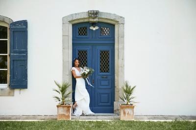 Allée de gravier bordée de rosiers roses en fleurs, entourée de pelouse et d'arbres en arrière-plan.