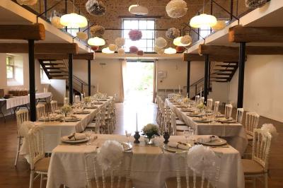 Allée de gravier bordée de rosiers roses en fleurs, entourée de pelouse et d'arbres en arrière-plan.