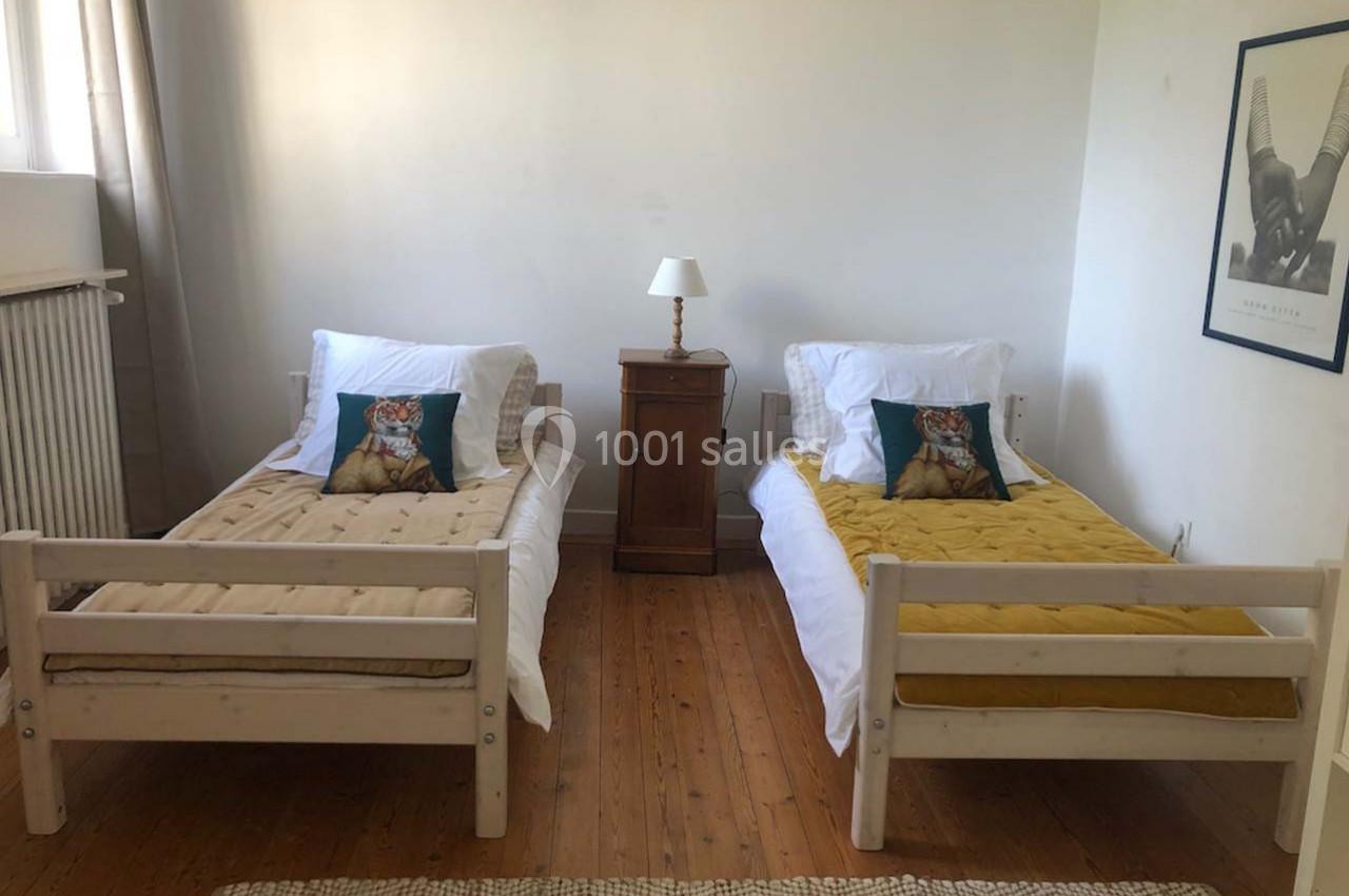 Deux lits simples avec des coussins à motif de tigre, une table de chevet centrale et un mur décoré d'un cadre.