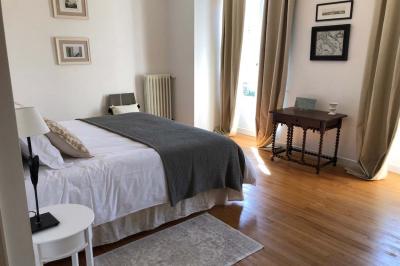 Allée de gravier bordée de rosiers roses en fleurs, entourée de pelouse et d'arbres en arrière-plan.