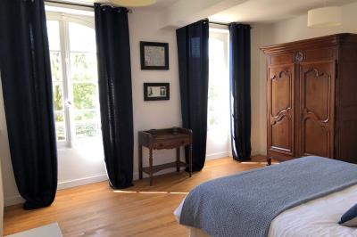 Allée de gravier bordée de rosiers roses en fleurs, entourée de pelouse et d'arbres en arrière-plan.