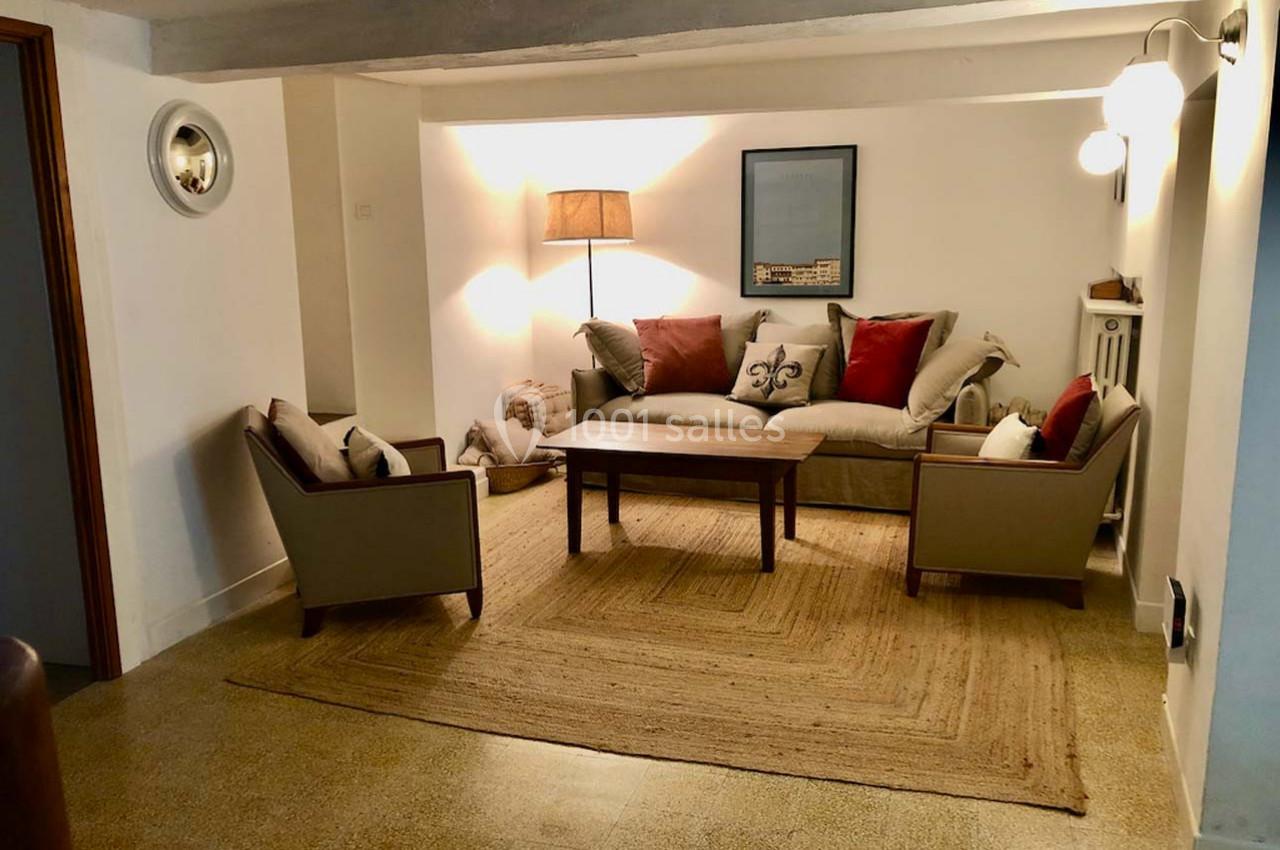 Salon avec canapé beige, coussins rouges et beiges, deux fauteuils assortis, table basse en bois et tapis en jute.