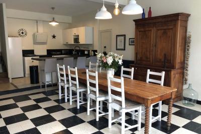 Allée de gravier bordée de rosiers roses en fleurs, entourée de pelouse et d'arbres en arrière-plan.