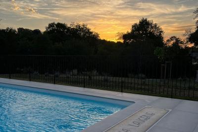 Allée de gravier bordée de rosiers roses en fleurs, entourée de pelouse et d'arbres en arrière-plan.