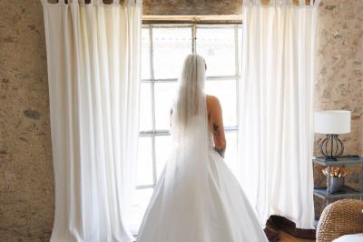 Allée de gravier bordée de rosiers roses en fleurs, entourée de pelouse et d'arbres en arrière-plan.