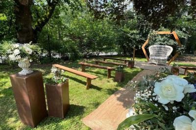 Allée de gravier bordée de rosiers roses en fleurs, entourée de pelouse et d'arbres en arrière-plan.