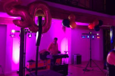 Allée de gravier bordée de rosiers roses en fleurs, entourée de pelouse et d'arbres en arrière-plan.