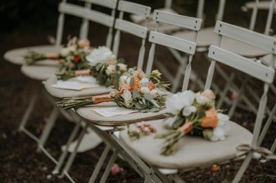 Allée de gravier bordée de rosiers roses en fleurs, entourée de pelouse et d'arbres en arrière-plan.