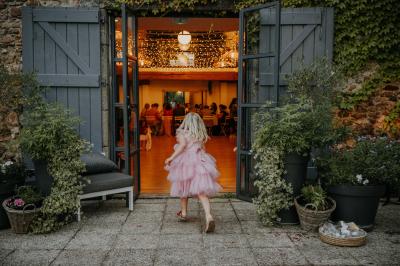 Allée de gravier bordée de rosiers roses en fleurs, entourée de pelouse et d'arbres en arrière-plan.