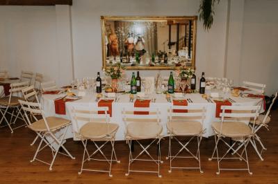 Allée de gravier bordée de rosiers roses en fleurs, entourée de pelouse et d'arbres en arrière-plan.