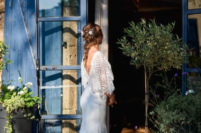 Allée de gravier bordée de rosiers roses en fleurs, entourée de pelouse et d'arbres en arrière-plan.