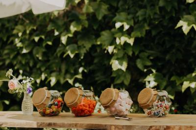 Allée de gravier bordée de rosiers roses en fleurs, entourée de pelouse et d'arbres en arrière-plan.